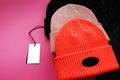 Collection of three hats in different colors with tags on bright background