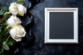 A collection of three white roses rests beside an empty picture frame on a dark surface. Royalty Free Stock Photo