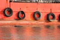 Collection of tires hanging with a chain on the side of a red ship for bumper protection Royalty Free Stock Photo