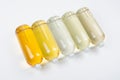 Collection transparent lying bottles with different pale colors liquid, cosmetic product, perfume or drink and silver cap.