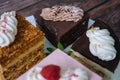 Collection of various cakes on wood background. Assortment of pieces slices with cream. Plate with different types of sweets.