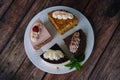 Collection of various cakes on wood background. Assortment of pieces slices with cream. Plate with different types of sweets.