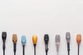 A collection of various microphones in different colors arranged in a row on a plain background Royalty Free Stock Photo