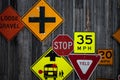 Collection of various road signs on rustic wooden wall