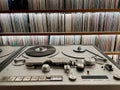 Collection of vintage vinyl records and tape machine in music studio.