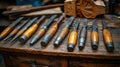 Collection of vintage wood carving tools arranged on a wooden workbench. Several chisels and gouges with wooden handles and metal Royalty Free Stock Photo