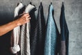 Collection of warm sweaters hanging on rack against graybackground