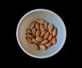 Collection Wet soaked almonds in a plastic bowl isolated on black.