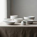 A collection of white ceramic dishware sits on a table covered with a beige tablecloth. Royalty Free Stock Photo