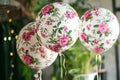 A collection of white and pink flowers delicately placed on top of a cluster of colorful balloons, Floral-printed balloons for a Royalty Free Stock Photo