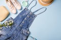 Collection of womens summer clothes and accessories collage on blue. Jeans overall and wicker hat, flat lay