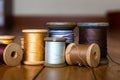 Black, Yellow, Gold, White, Silver, Dark Grey, and Beige Threads on Wooden Spools On Several Planks of Light Wood