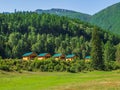 Collective camping, tourist complex, wooden guest houses against the background of fir-covered high mountains