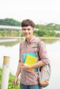 College asian male student holding book on the park