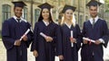 College graduates in academic regalia holding diplomas, celebrating graduation Royalty Free Stock Photo