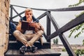 College student with backpack reading book walking in autumn park sitting on stairs