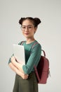 College student girl isolated on gray background, smiling at camera, pressing laptop to chest, wearing backpack, ready to go to Royalty Free Stock Photo
