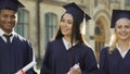 College student in graduation outfit with diplomas smiling, education abroad