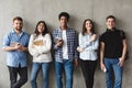 College students with books smiling to camera over grey wall Royalty Free Stock Photo