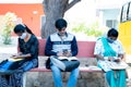 College students with face mask busy using mobile at university campus during leisure or break time - concept of new normal