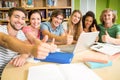 College students gesturing thumbs up in library Royalty Free Stock Photo