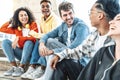 College students having sun sitting in university campus - Multiracial young people talking and laughing together hanging outside Royalty Free Stock Photo