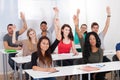 College students raising hands in classroom Royalty Free Stock Photo