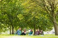 College students sitting on grass in park Royalty Free Stock Photo