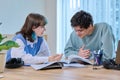 College students teenage guy girl talking sitting together at desk in classroom Royalty Free Stock Photo