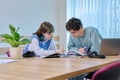 College students teenage guy girl talking sitting together at desk in classroom Royalty Free Stock Photo
