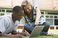 College students using laptop on campus lawn