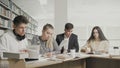 College students working together preparing for exams while sitting at table at university library Royalty Free Stock Photo