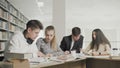 College students working together preparing for exams while sitting at table at university library Royalty Free Stock Photo