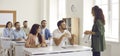 Coach having discussion with group of happy people who are sitting at desks in classroom Royalty Free Stock Photo