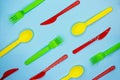 Colofulr plastic cutlery on light blue background. Pattern of green forks, yellow spoons and red knives Royalty Free Stock Photo