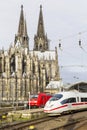 COLOGNE, GERMANY - April 7 2018: Rear view of Cologne railway station with red and white trains. Cathedral tower on background