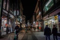 COLOGNE, GERMANY - NOVEMBER 5, 2022: Selective blur on a crowd of people walking on Hohe Strasse street at night, with shops & Royalty Free Stock Photo