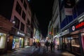 COLOGNE, GERMANY - NOVEMBER 5, 2022: Selective blur on young people aking on Hohe Strasse street at night, with shops and stores. Royalty Free Stock Photo