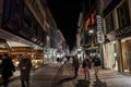 COLOGNE, GERMANY - NOVEMBER 5, 2022: Selective blur on young people aking on Hohe Strasse street at night, with shops and stores. Royalty Free Stock Photo