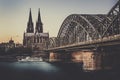 UNESCO Cathedral in Cologne Germany and Hohenzollern Bridge across Rhine River with Boat at Evening Sunset Royalty Free Stock Photo