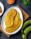 COLOMBIAN CARIBBEAN CENTRAL AMERICAN FOOD. Patacon or toston, fried and flattened whole green plantain banana on white Royalty Free Stock Photo