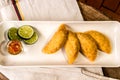 Colombian empanada with spicy sauce on wooden background