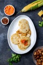 COLOMBIAN FOOD. Maize AREPAS and fried pork chicharron ans colombian tomato sauce. Top view. Black background Royalty Free Stock Photo