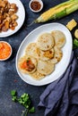 COLOMBIAN FOOD. Maize AREPAS and fried pork chicharron ans colombian tomato sauce. Top view. Black background Royalty Free Stock Photo