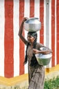 Unknown young woman carry water container back from community