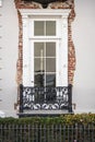 A colonial ear window with a small balcony with eroded stucco siding revealing the underlying brick Royalty Free Stock Photo