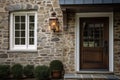 colonial house exterior with stone wall, wooden door, and lantern