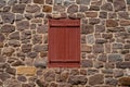 closed red antique window shutters with stone wall surrounding Royalty Free Stock Photo