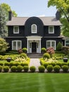 Colonial style brick family house exterior with black roof tiles. Beautiful front yard with lawn and flower bed Royalty Free Stock Photo