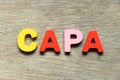 Color letter in word CAPA abbreviation of corrective action and preventive action on wood background